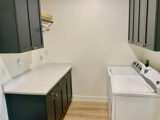 Laundry room featuring cabinet space, light wood-style floors, and washer and clothes dryer