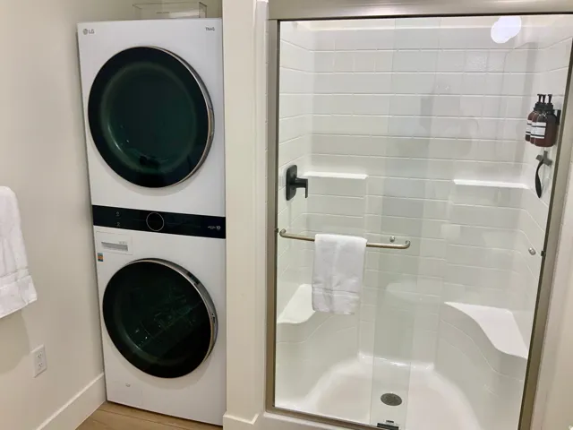 Full bathroom with stacked washer / drying machine and a stall shower