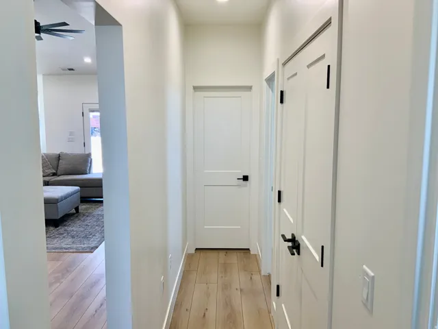 Hallway with light wood-type flooring and recessed lighting