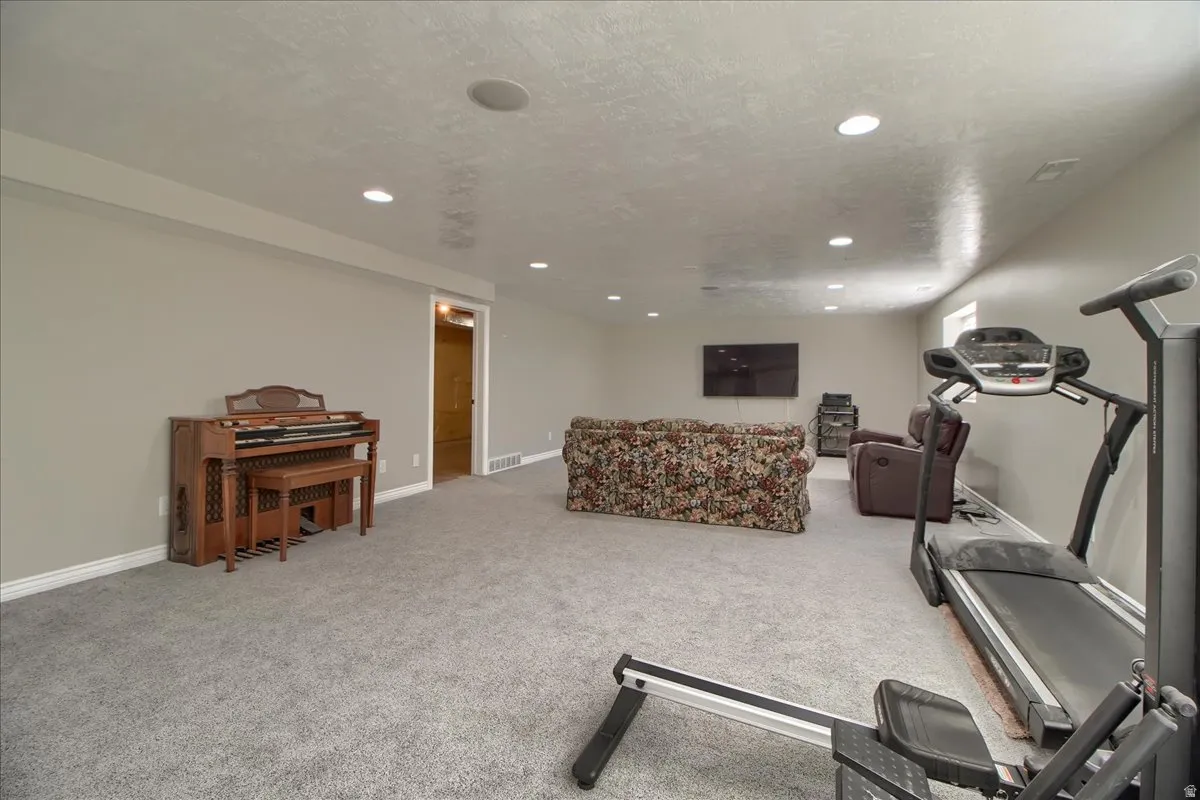 Workout area featuring light carpet, a textured ceiling, and recessed lighting