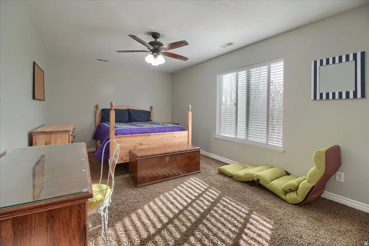 Carpeted bedroom with ceiling fan and baseboards