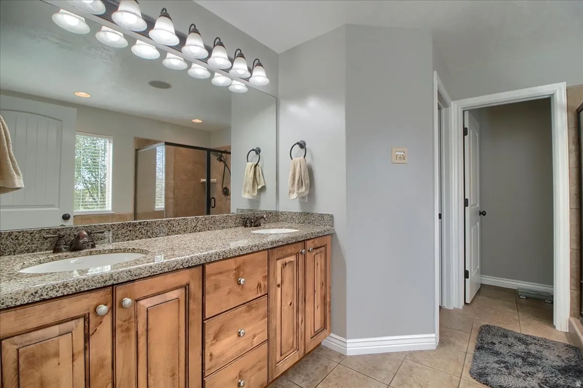 Bathroom with double vanity, a shower stall, and light tile patterned flooring