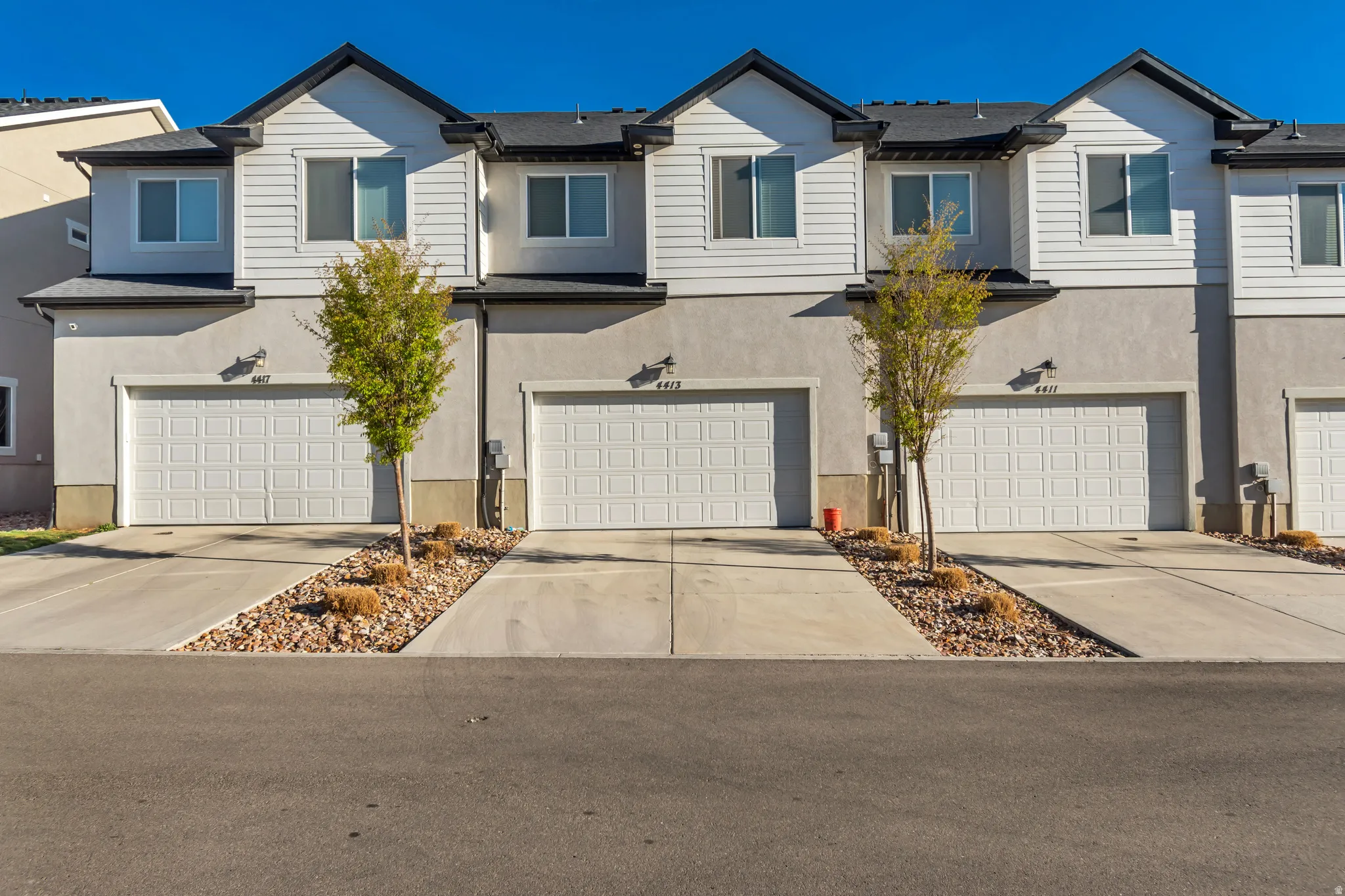 View of front of home featuring an attached garage, concrete driveway, and stucco siding