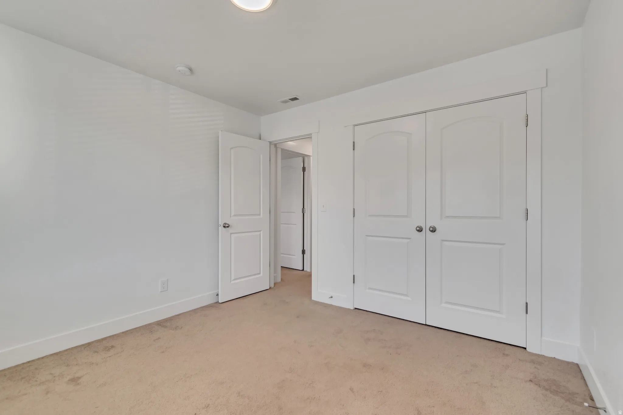 Unfurnished bedroom featuring light carpet and a closet