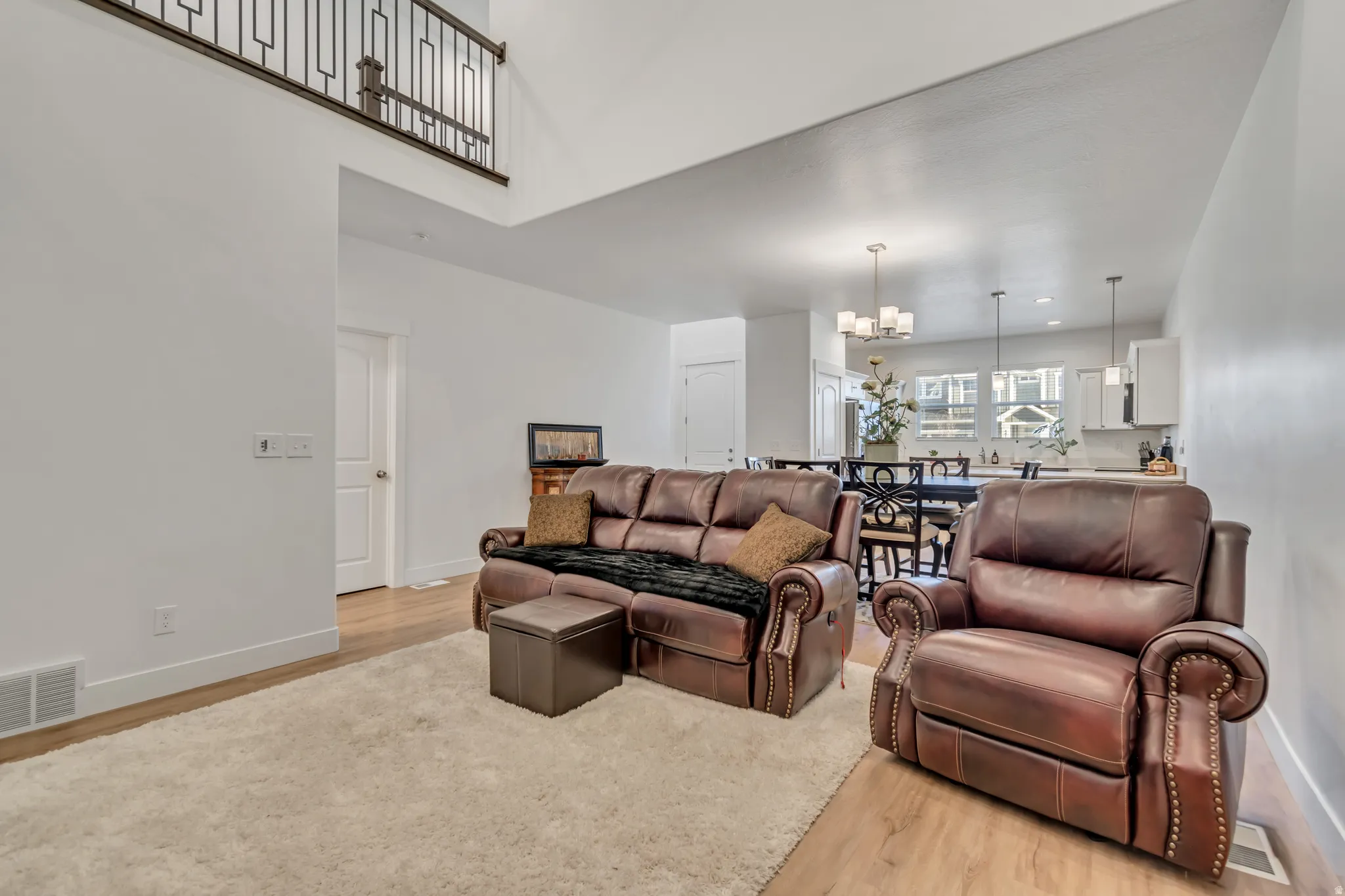 Living room with light wood finished floors and suspended lighting
