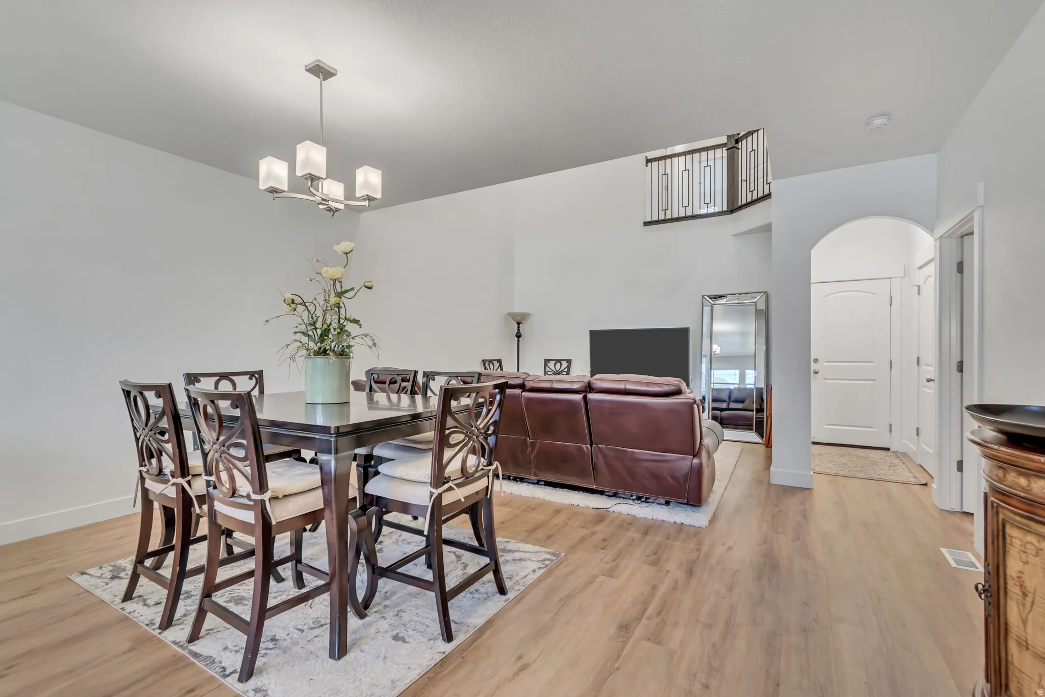 Dining space with arched walkways, light wood finished floors, and a chandelier