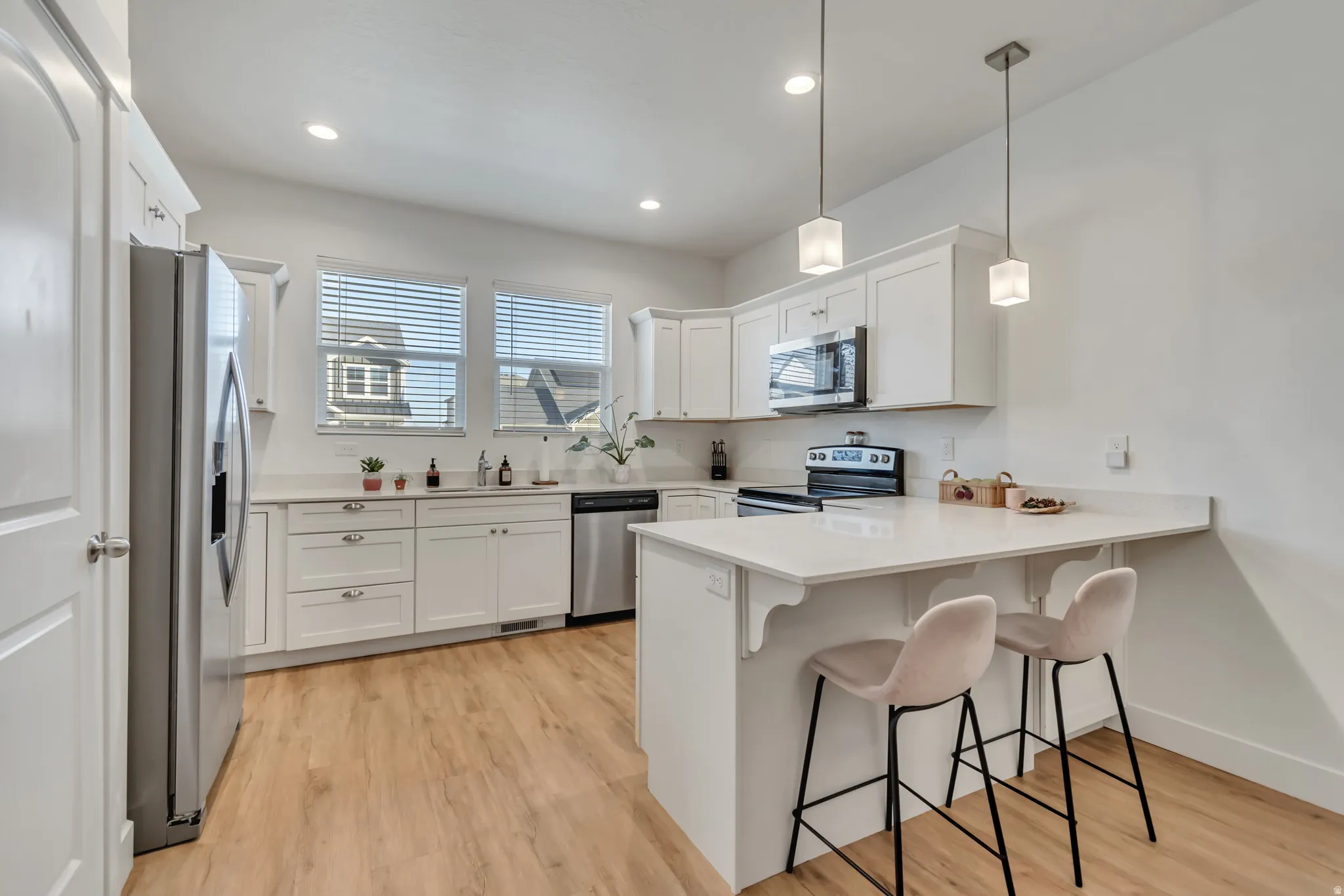 Kitchen with a kitchen bar, a peninsula, white cabinets, and light wood-type flooring