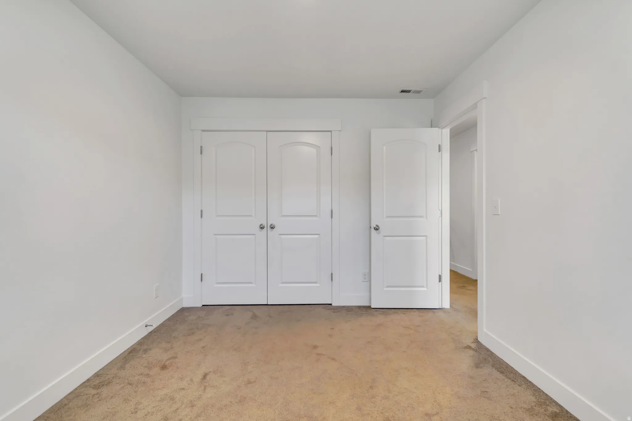 Unfurnished bedroom featuring light colored carpet and a closet