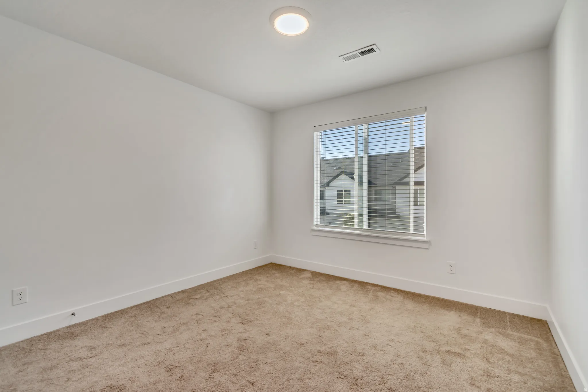 Empty room featuring light carpet and baseboards