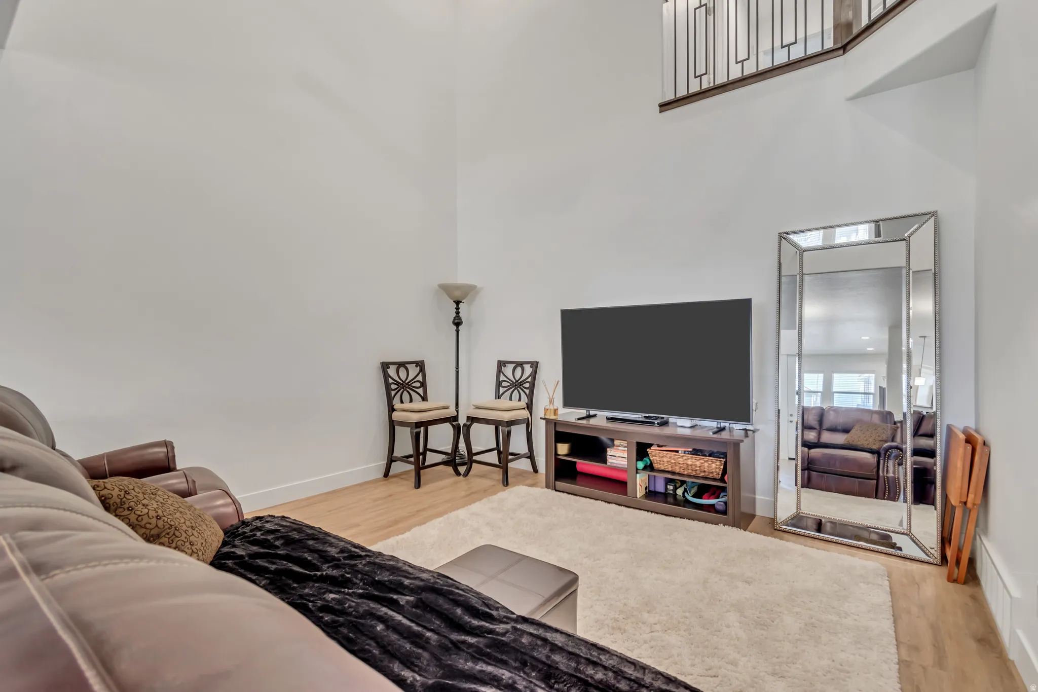 Living room featuring light wood-style flooring and a high ceiling