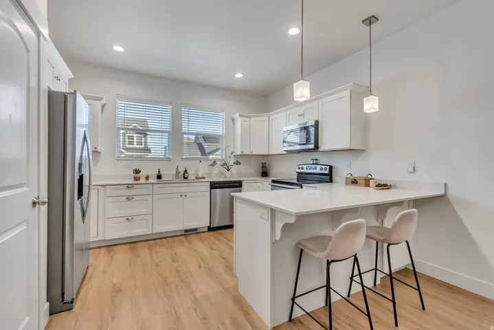 Kitchen with a kitchen bar, a peninsula, white cabinets, and light wood-type flooring
