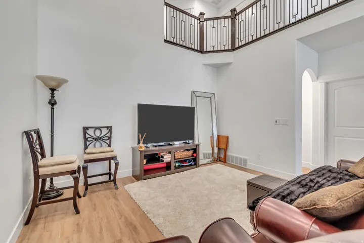 Living area with arched walkways, light wood-style floors, and a high ceiling