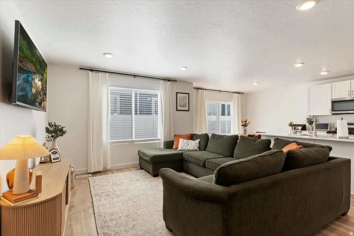 Living room with recessed lighting, light wood-style flooring, and a textured ceiling