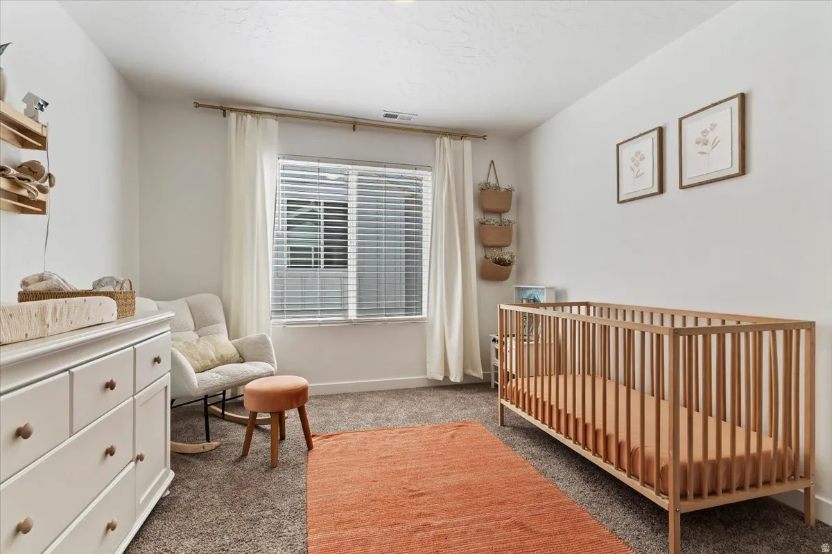 Bedroom with a nursery area and carpet