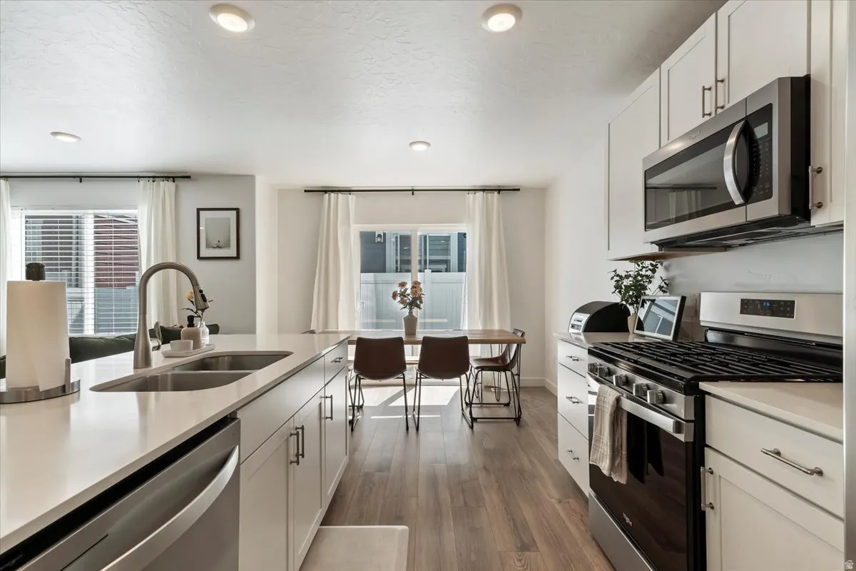 Kitchen featuring stainless steel appliances, white cabinets, dark wood-style floors, recessed lighting, and a textured ceiling