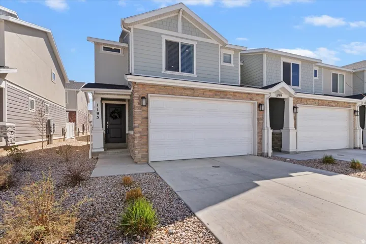 Craftsman house with stone siding, driveway, and an attached garage