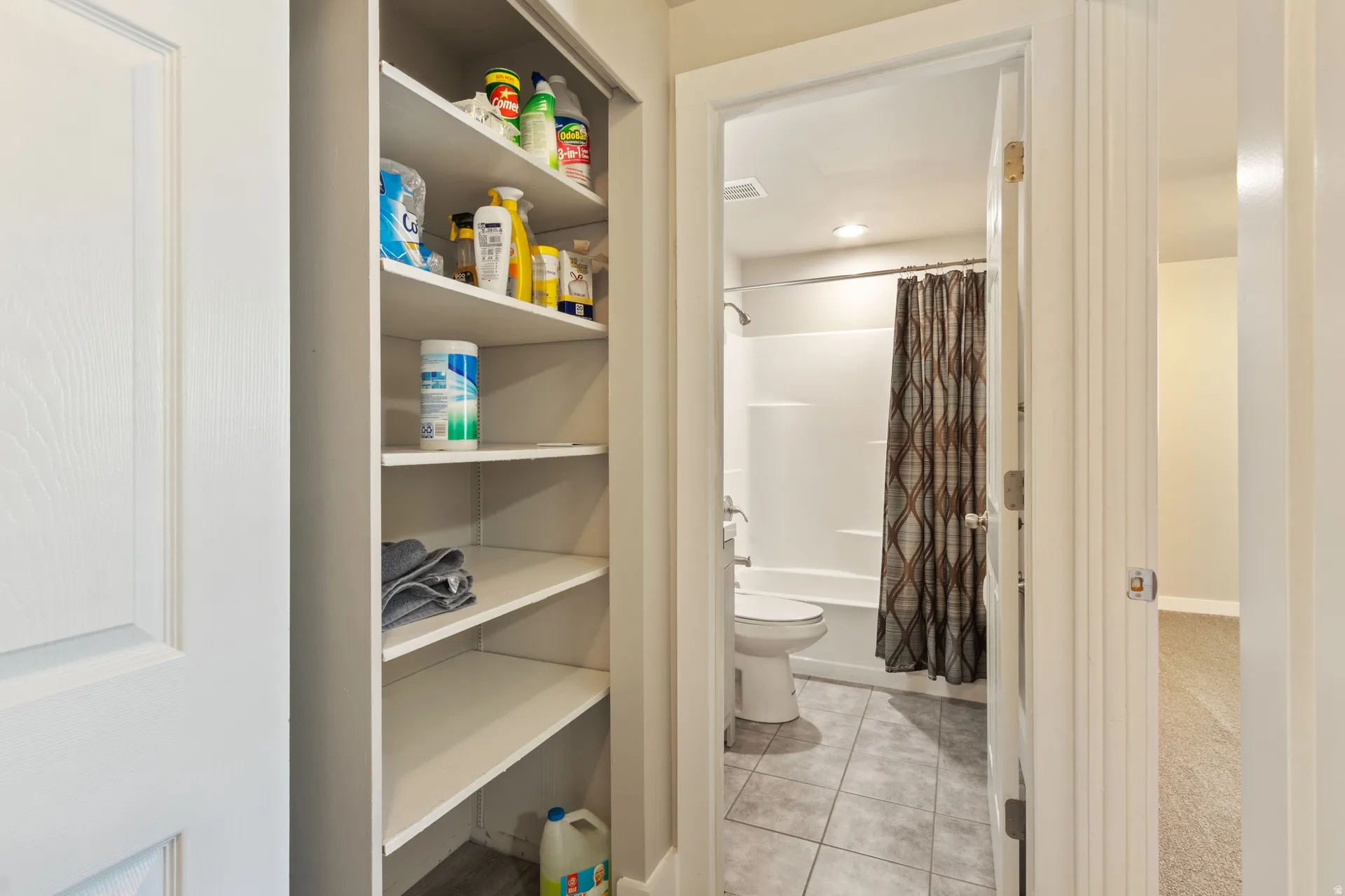 Bathroom with shower / bath combo with shower curtain, a closet, and light tile patterned flooring