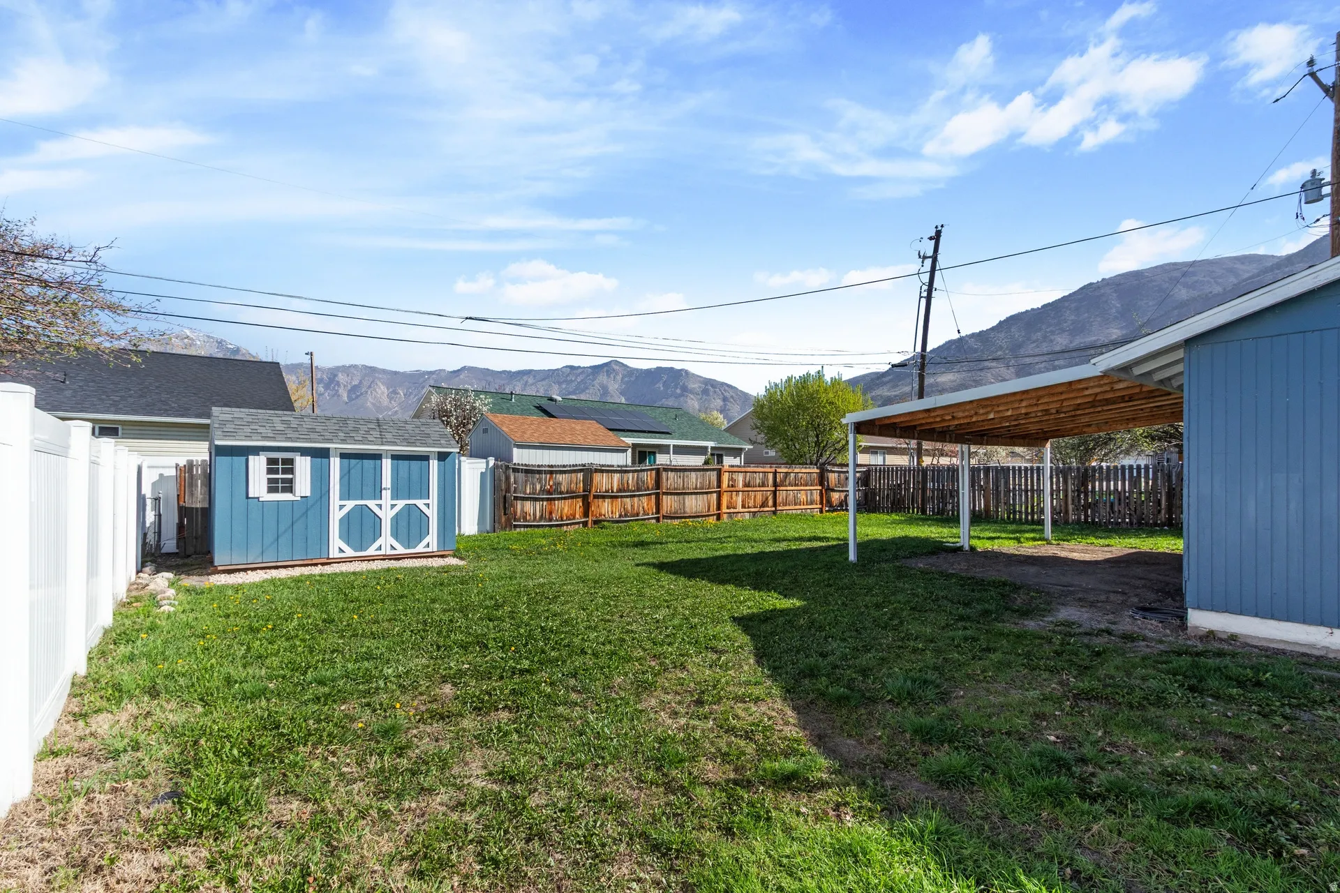 Fenced backyard with a storage unit and a mountain view