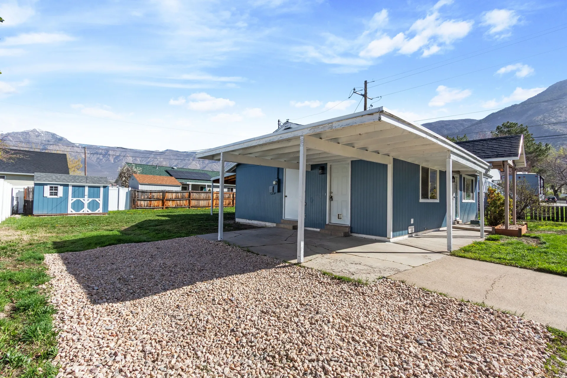 Rear view of house featuring a mountain view, a storage shed, a carport, and a patio area