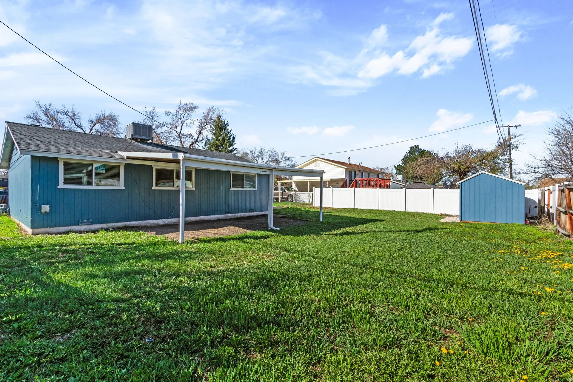 Rear view of house with a fenced backyard, a storage shed, and roof with shingles