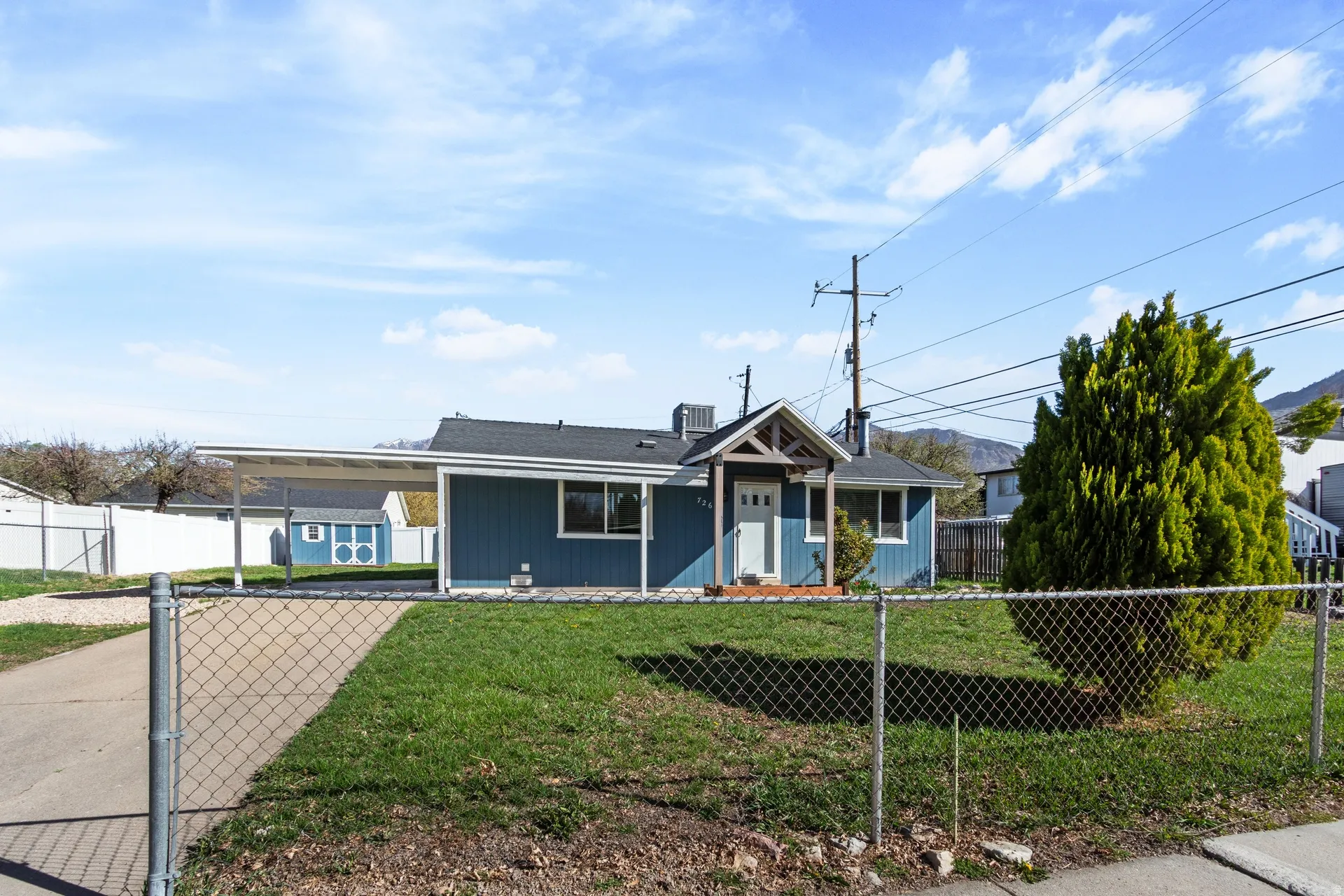 Ranch-style home featuring an attached carport and a fenced front yard