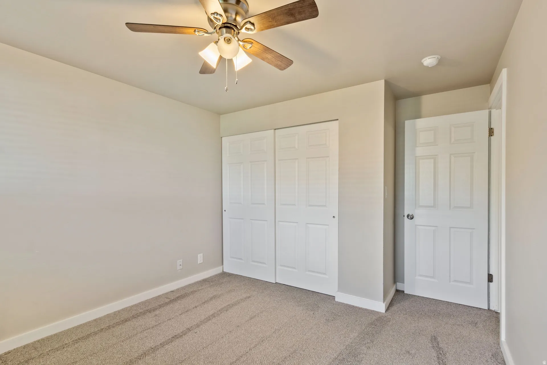 Unfurnished bedroom with light colored carpet, a closet, and a ceiling fan