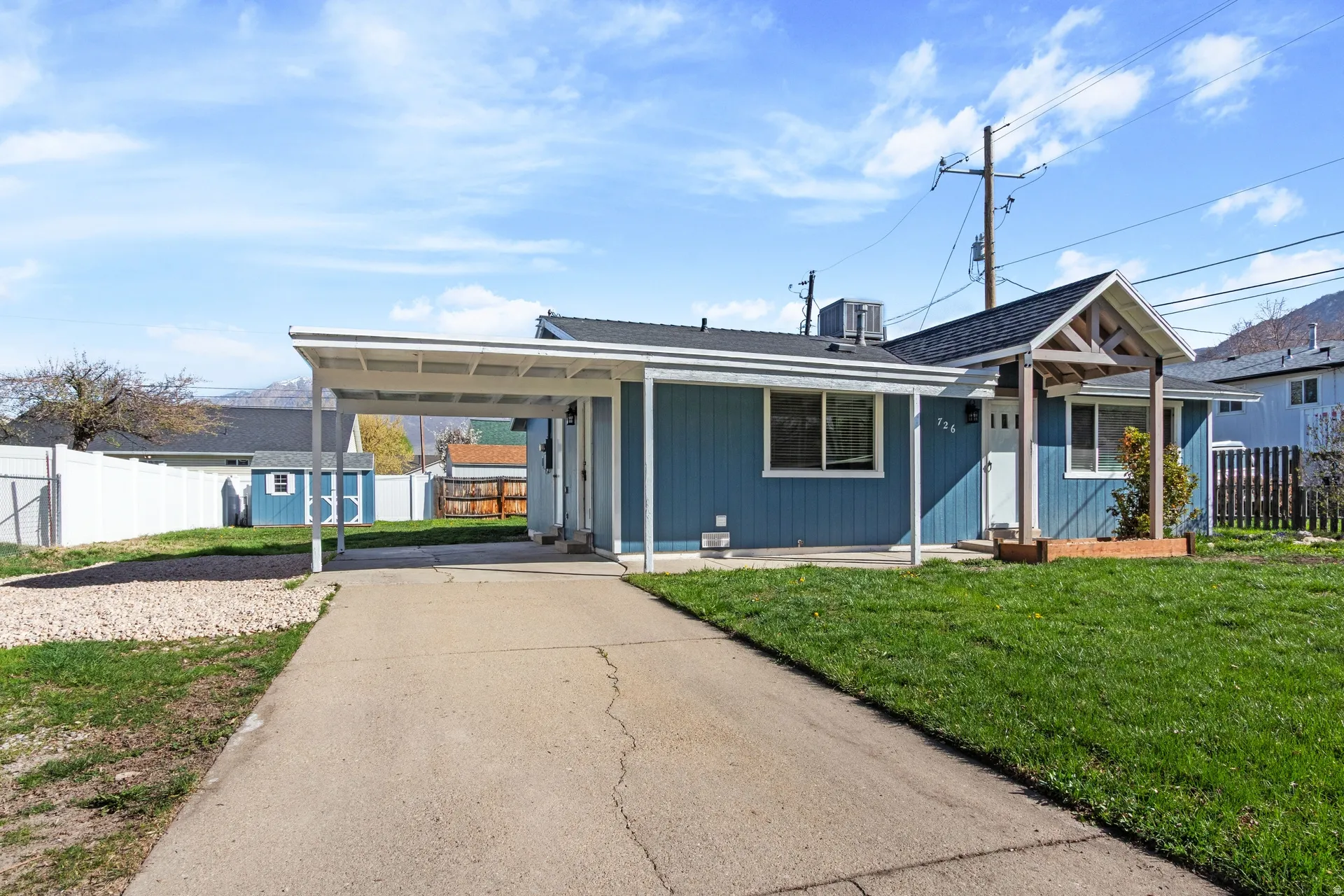 View of front facade featuring driveway, an attached carport, and roof with shingles