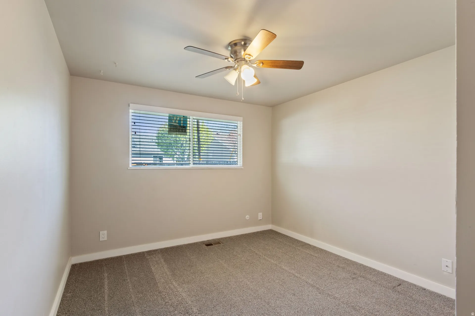 Spare room featuring light colored carpet and a ceiling fan