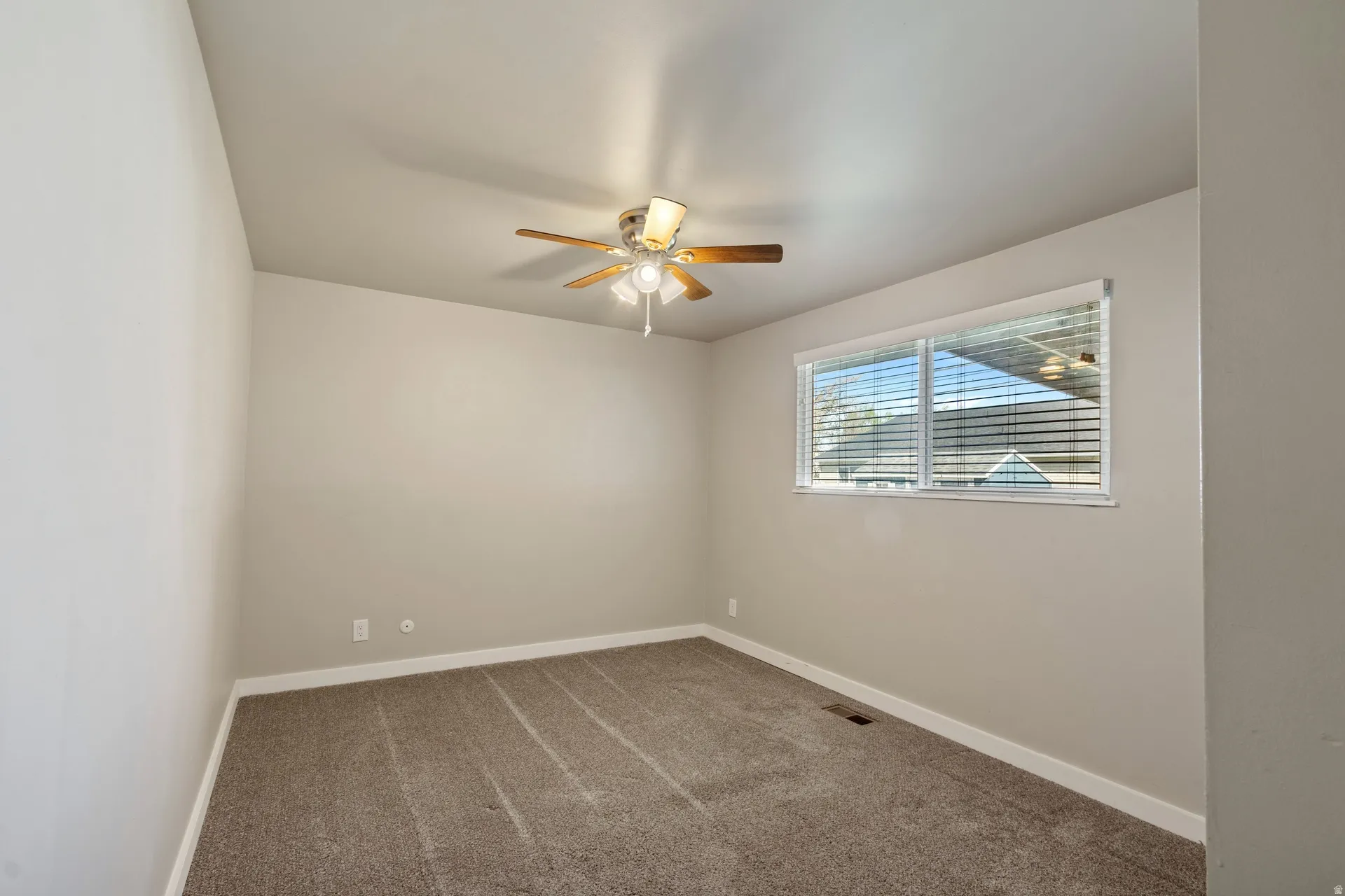 Carpeted spare room featuring baseboards and a ceiling fan