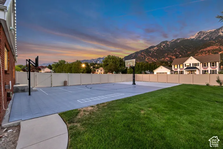 Expansive sport court with two basketball hoops, a surrounding privacy fence, and a manicured lawn area
