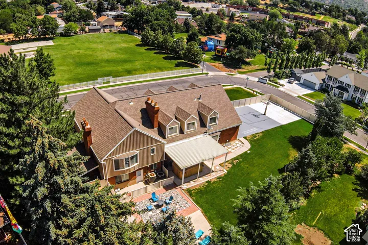 Expansive property featuring a large green space, mature trees, a dedicated sports court, and a covered patio