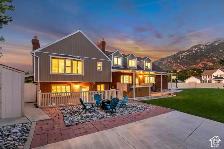 Expansive backyard featuring a manicured lawn, an outdoor entertainment area with a fire pit, a paved patio, and swim spa