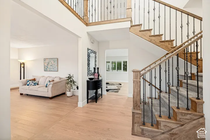 Hardwood flooring throughout, a grand staircase with wrought iron balusters and wood handrails, and an open entryway