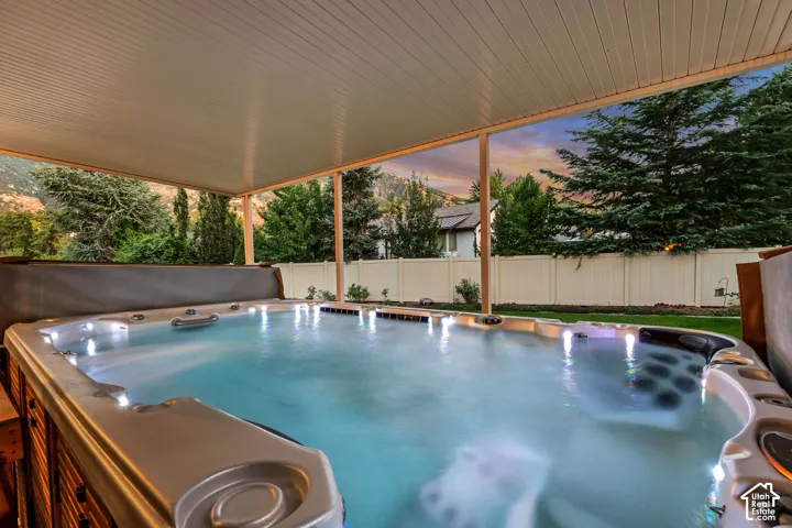 Covered swim spa with integrated lighting, wood-finish paneling, and a surrounding privacy fence
