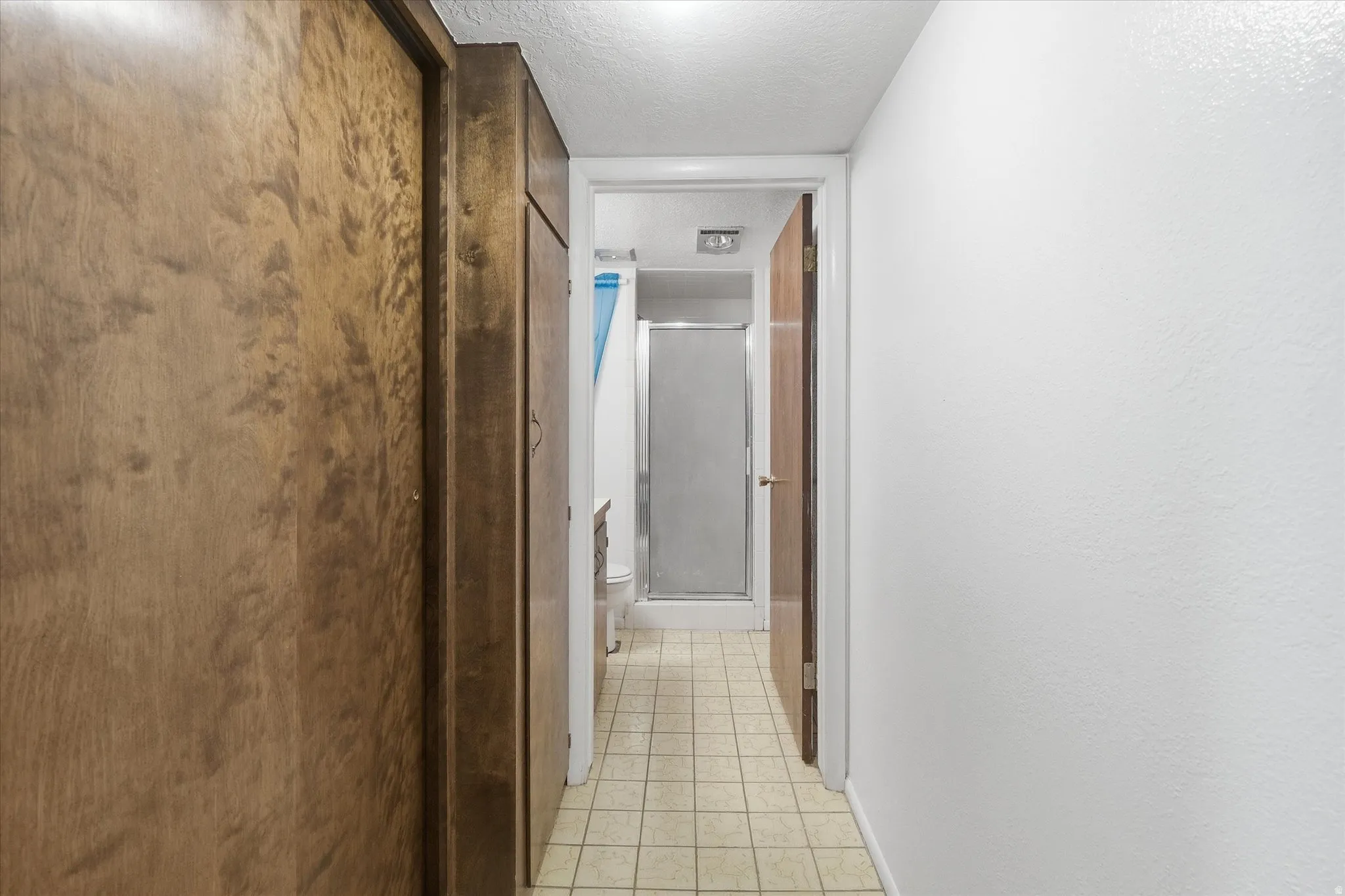 Hall featuring a textured ceiling and baseboards