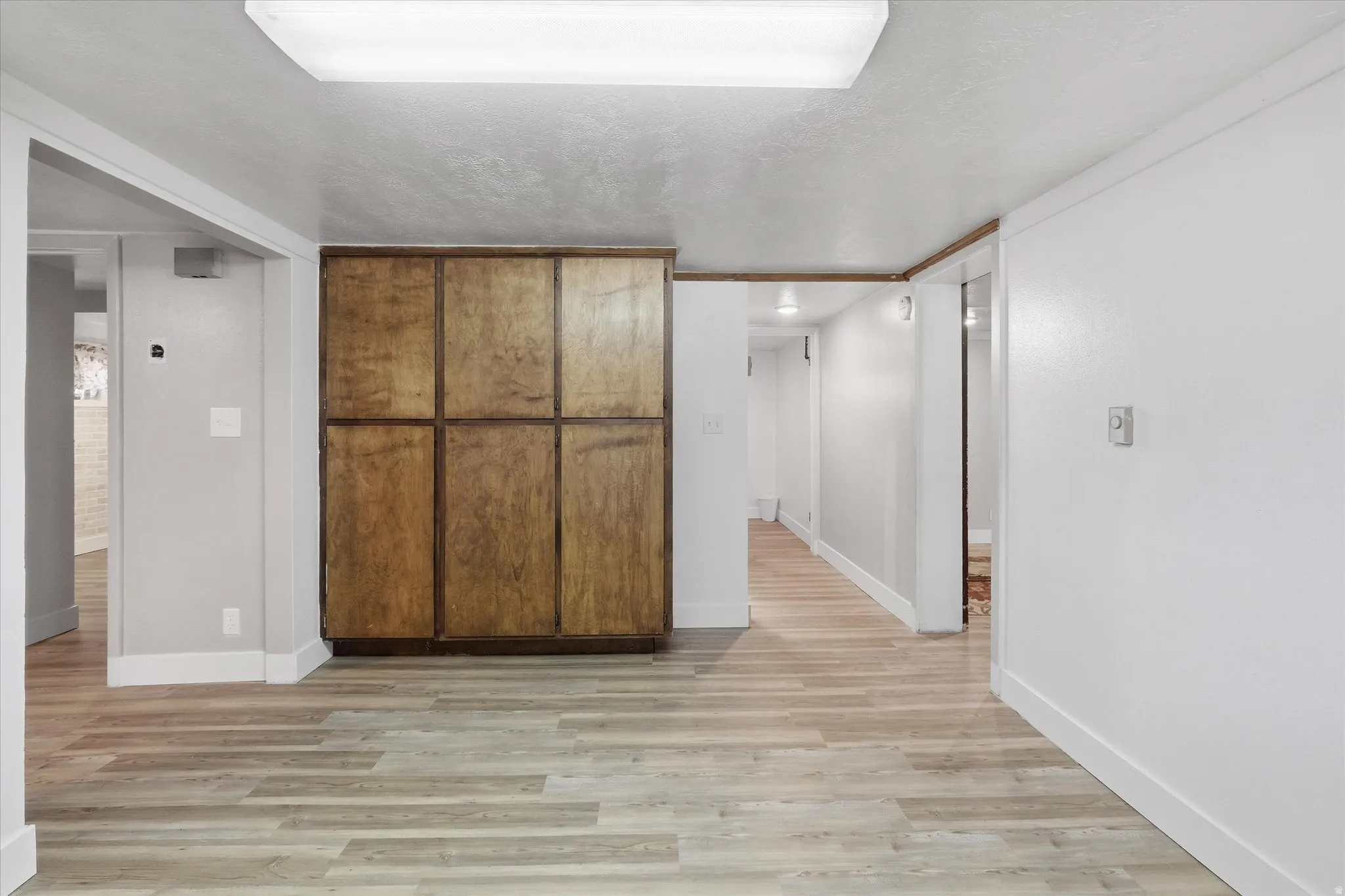 Hall featuring light wood-style floors and a textured ceiling