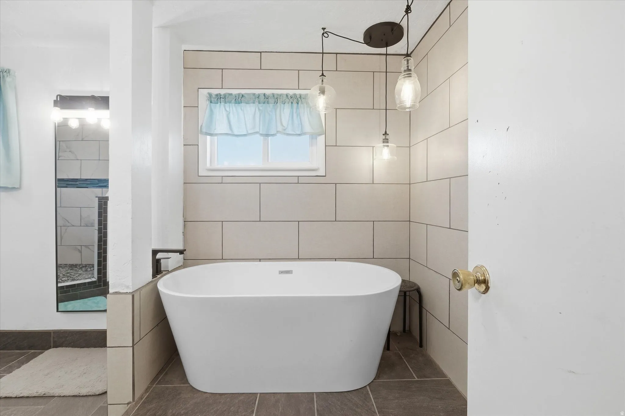 Bathroom featuring a freestanding tub, tile walls, tiled shower, and tile patterned floors