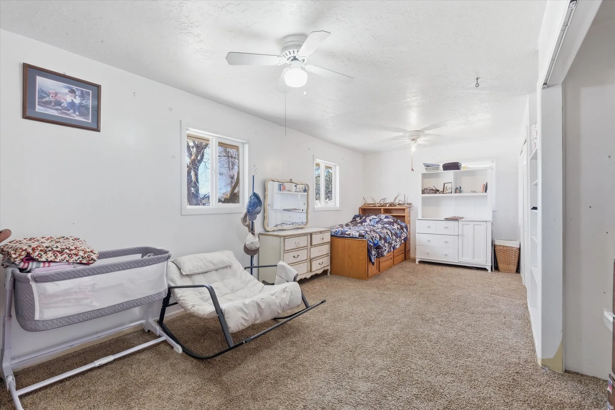 Bedroom with light carpet, ceiling fan, and a textured ceiling