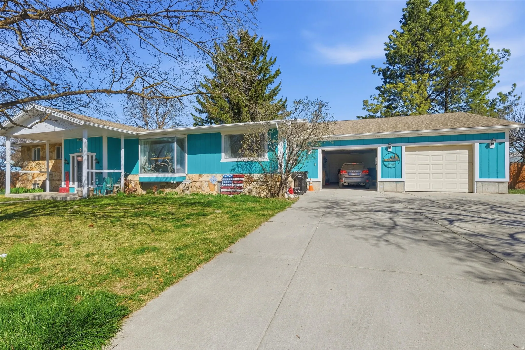 Ranch-style home featuring a front lawn, driveway, an attached garage, and roof with shingles