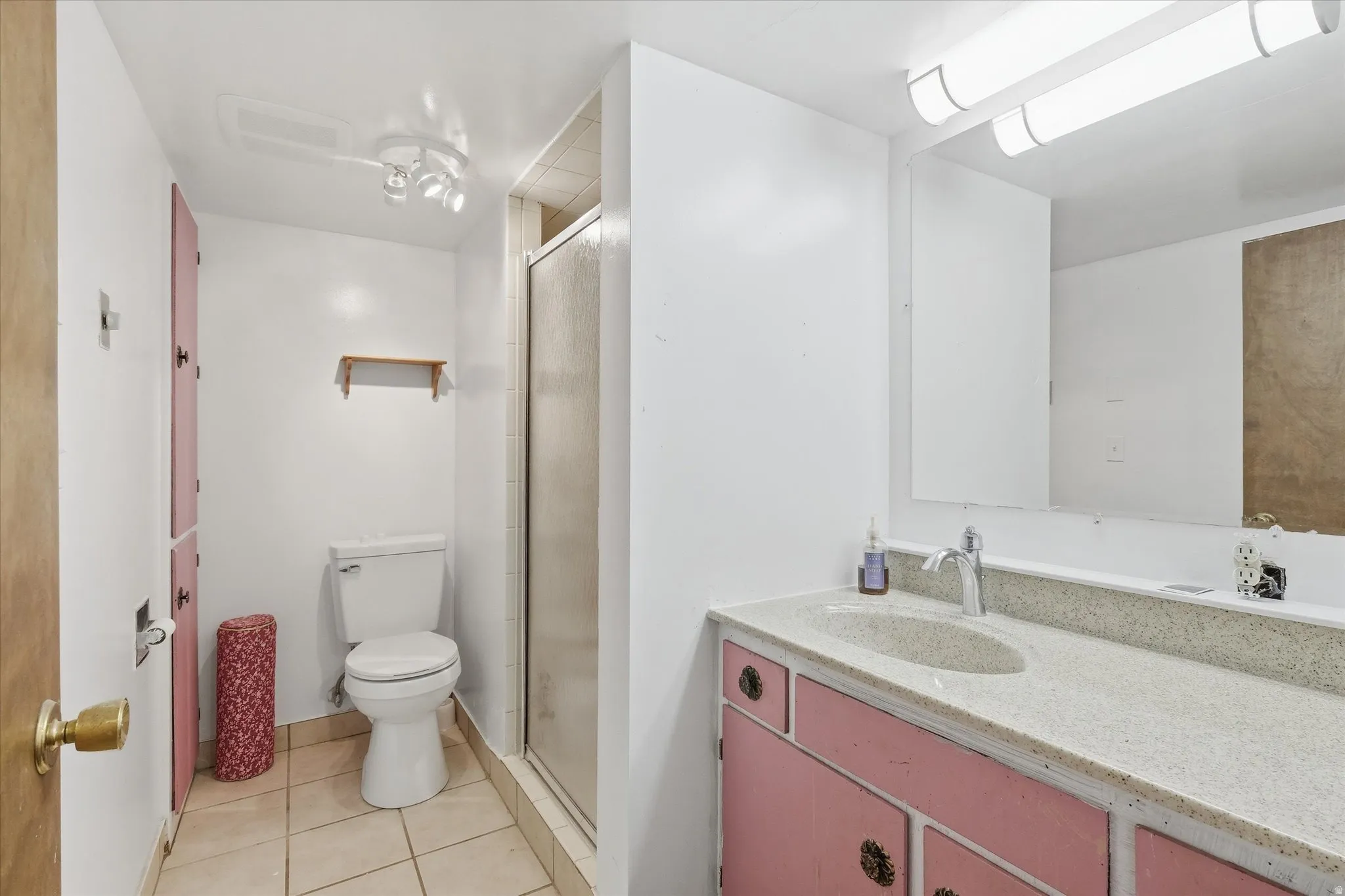 Bathroom featuring vanity, light tile patterned flooring, and a stall shower