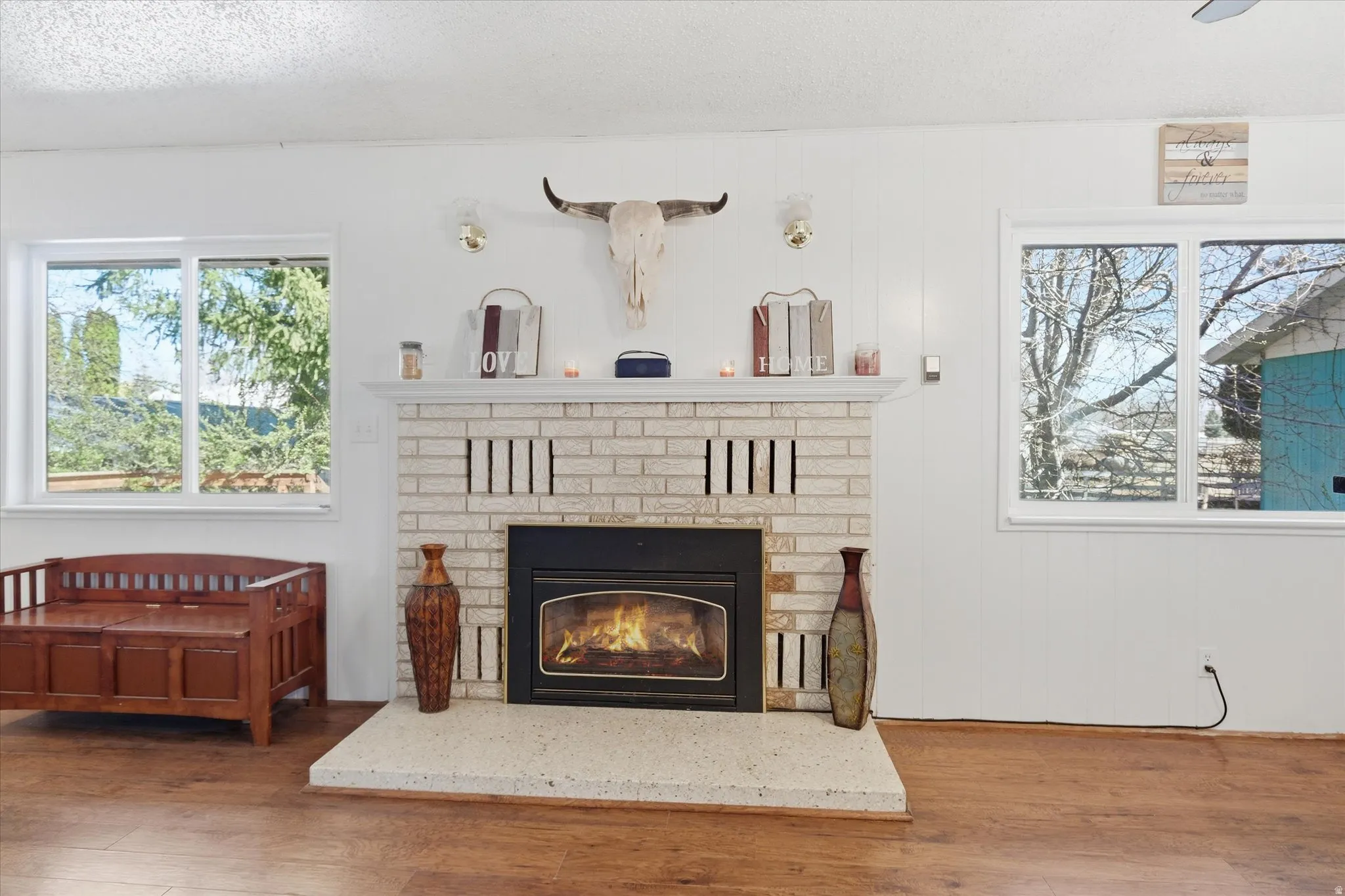Detailed view of wood finished floors, a fireplace, and a textured ceiling