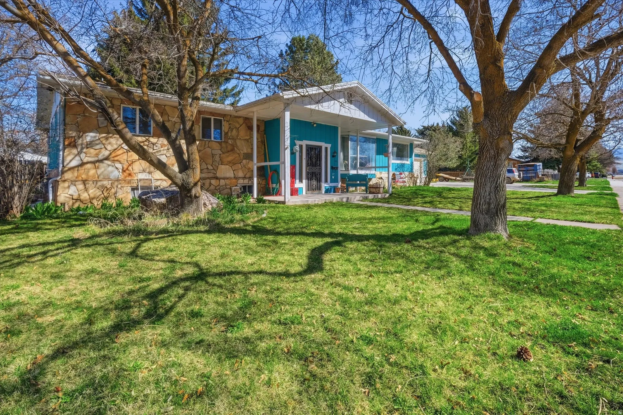 Front of property with a lawn and stone siding