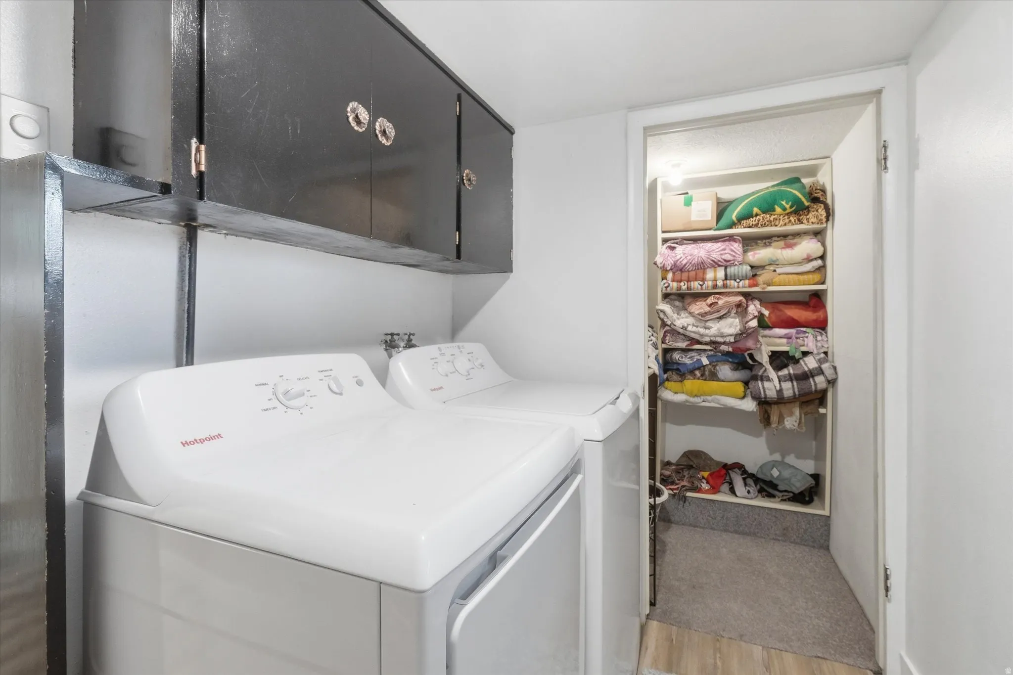 Laundry room with cabinet space, light wood-style floors, and washing machine and clothes dryer