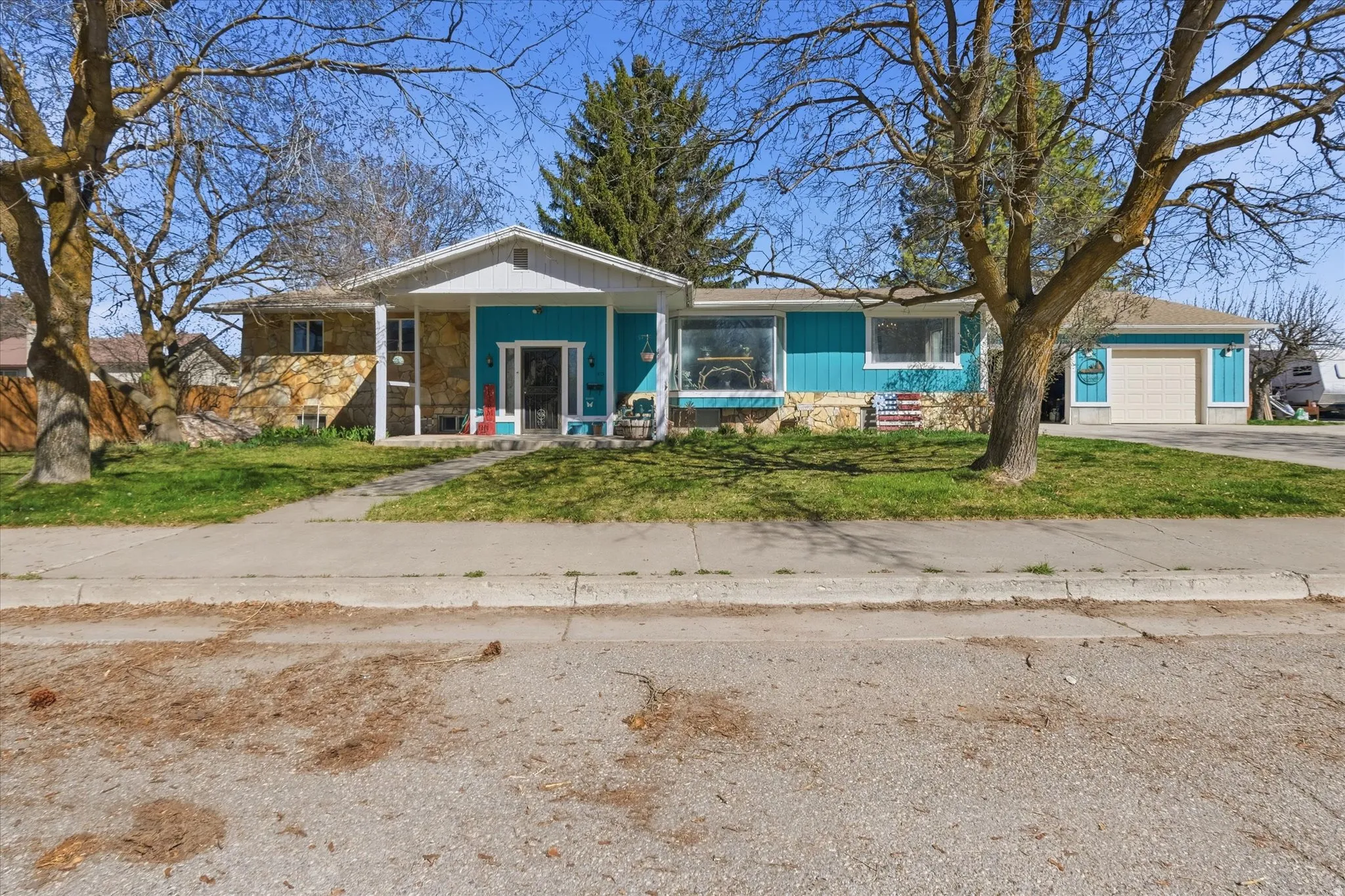 View of front of house with covered porch, a front lawn, a garage, and driveway