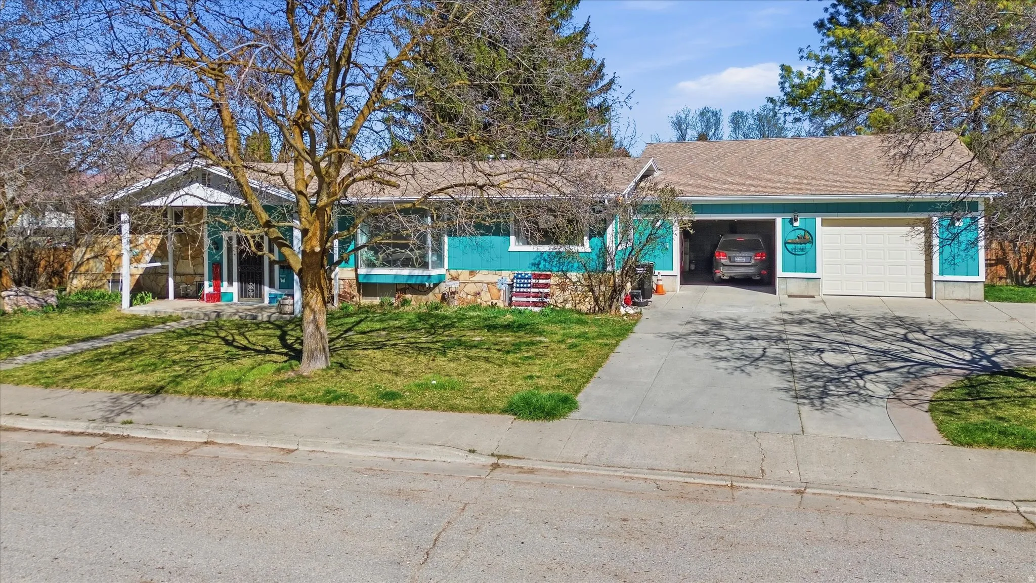 Single story home with concrete driveway, a garage, a front lawn, and a shingled roof