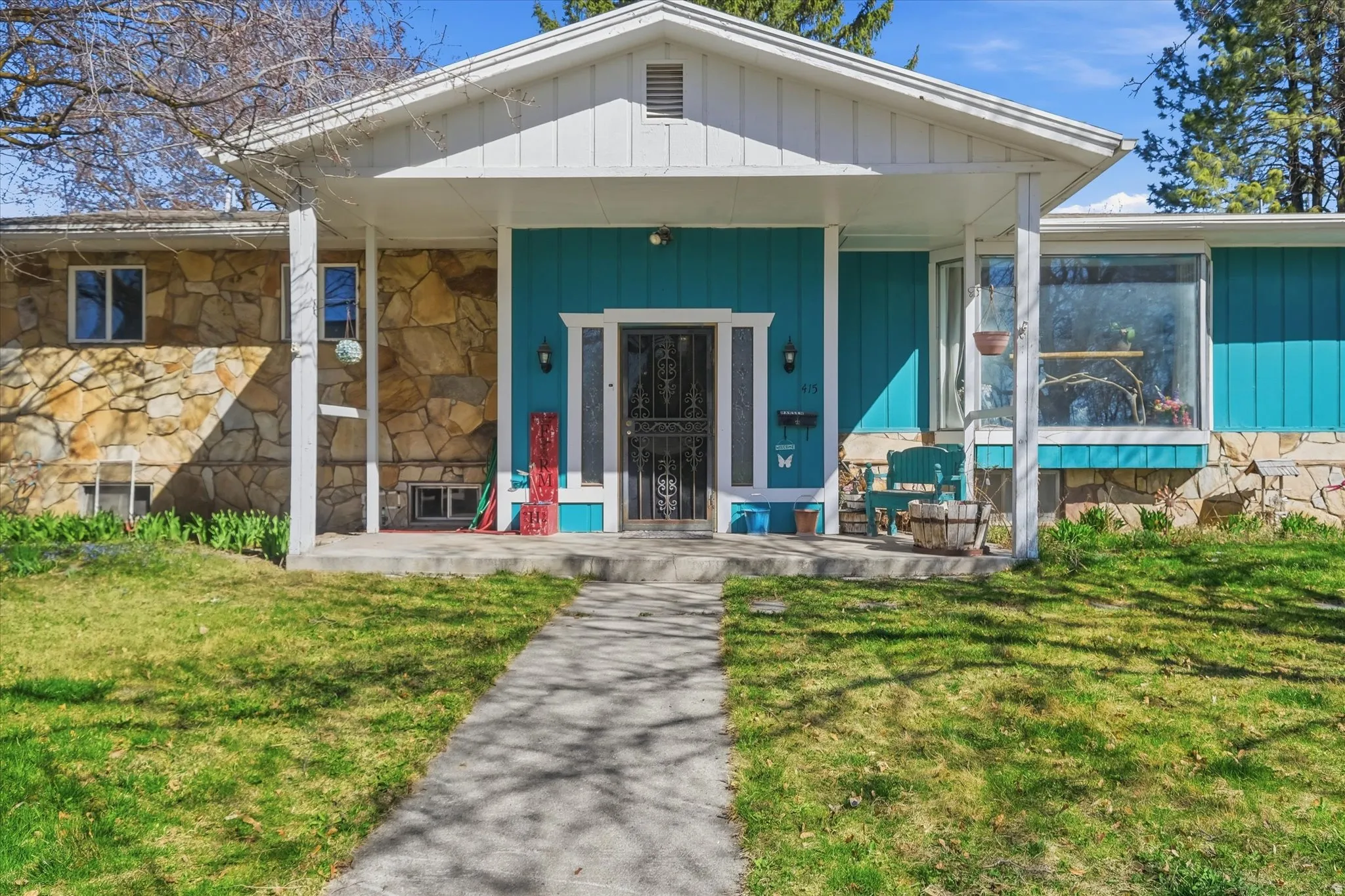 Doorway to property featuring a porch, a yard, and stone siding on one side with vertical exterior siding on the rest of the home