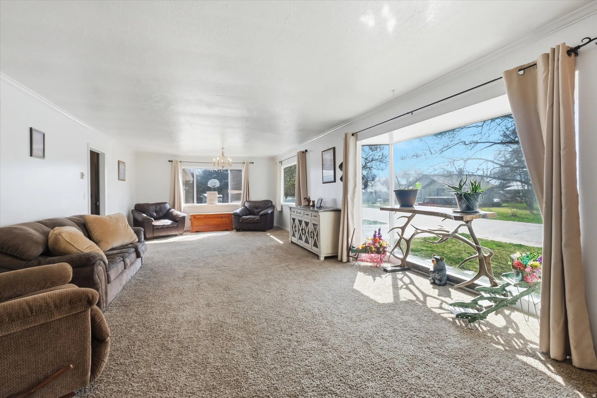 Carpeted living area with suspended lighting and ornamental molding