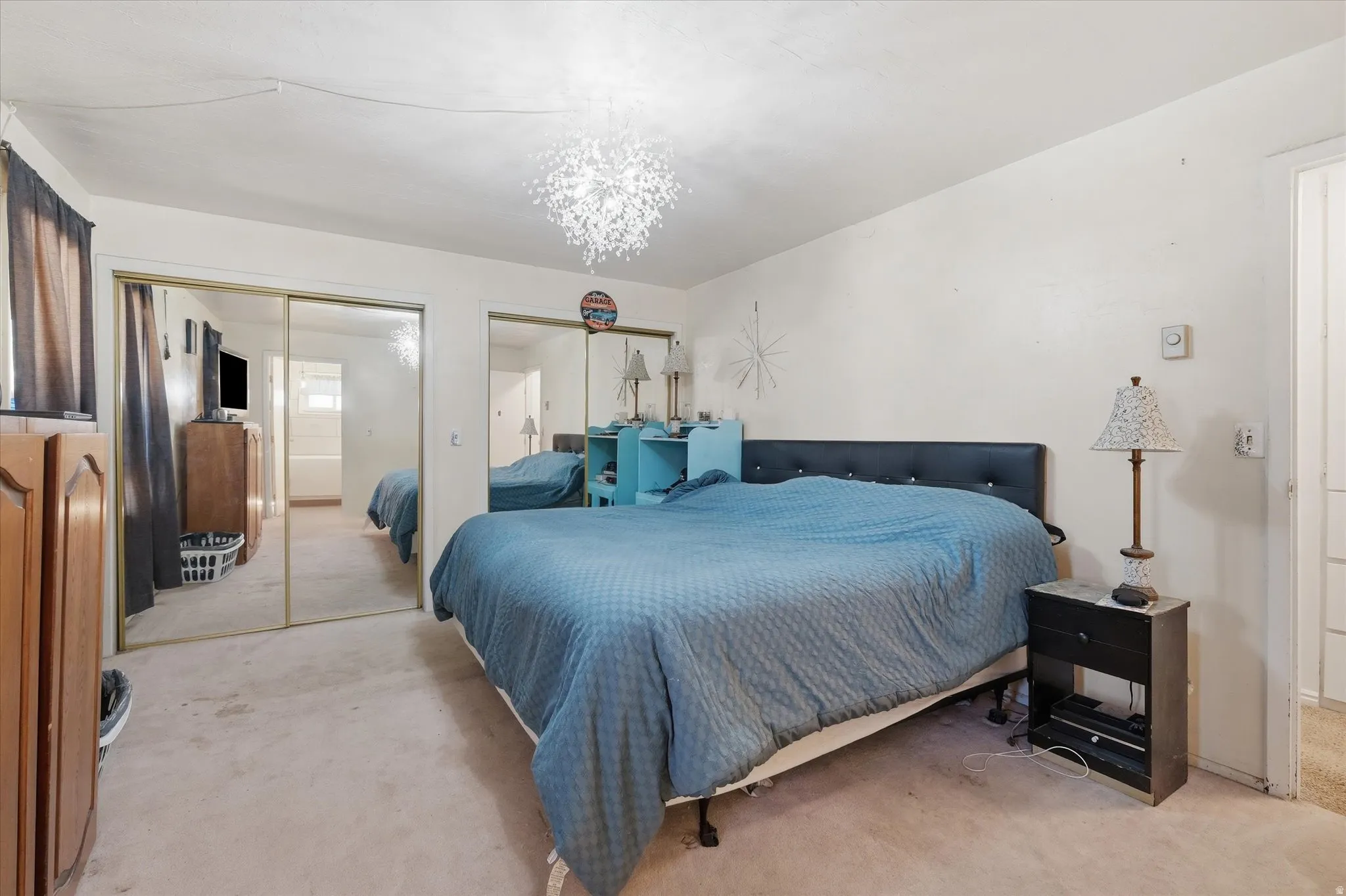Bedroom featuring multiple closets, light carpet, and hanging lights