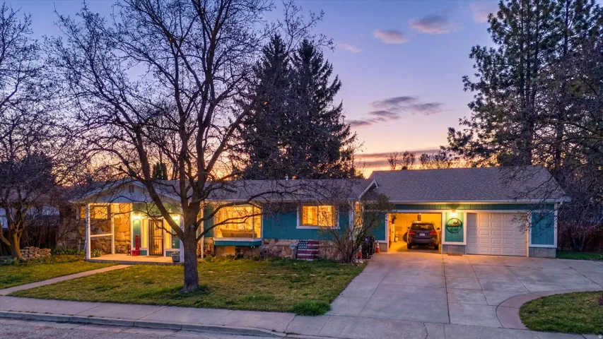 Ranch-style house with an attached garage, a front yard, driveway, and covered porch