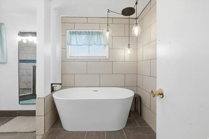 Bathroom featuring a freestanding tub, tile walls, tiled shower, and tile patterned floors